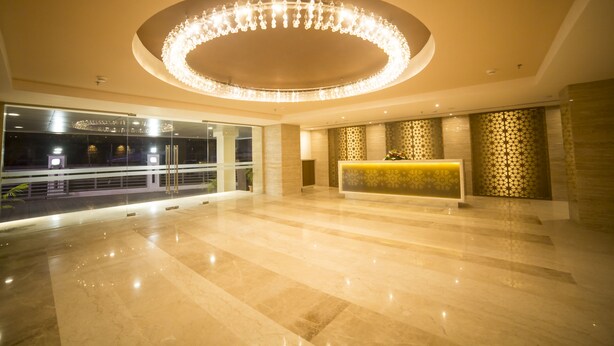 Un hall espacioso con un candelabro circular, una mesa de recepción y un papel tapiz estampado.
