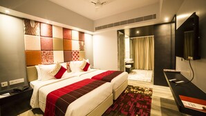 Una habitación de hotel con una cama grande, un escritorio, un espejo y un televisor.