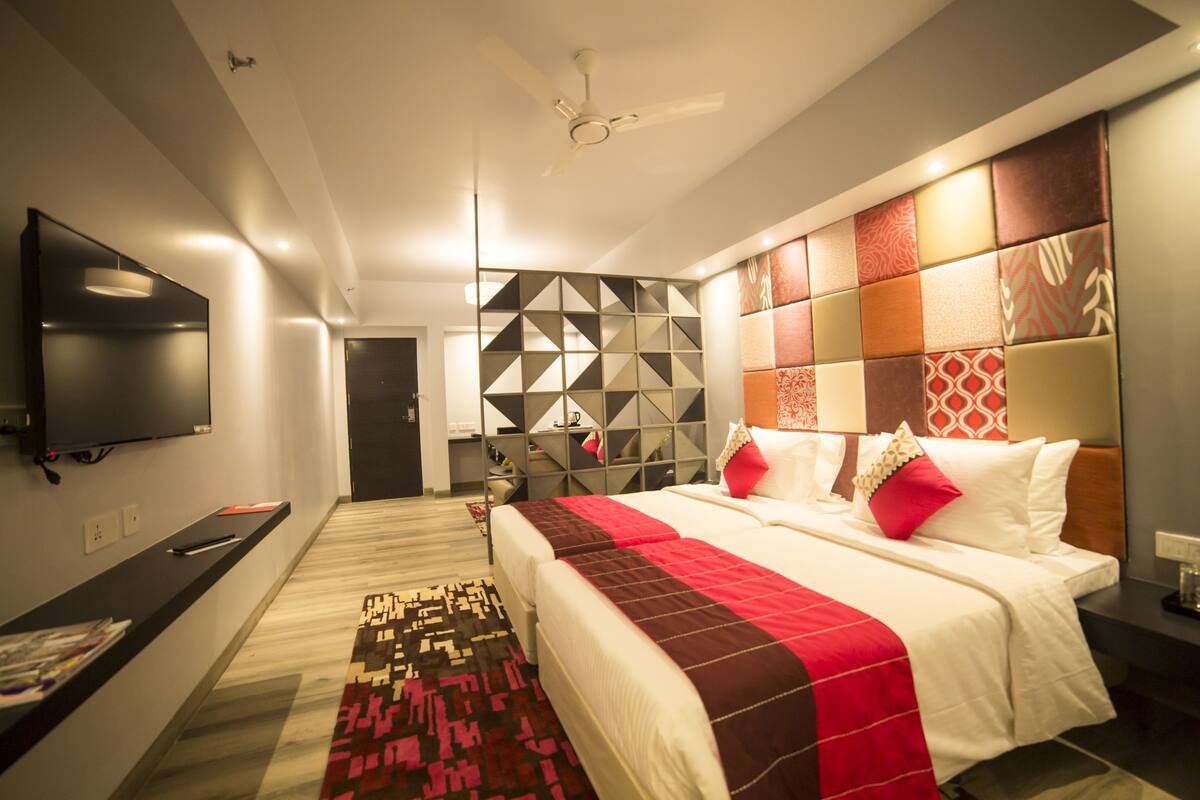 Una habitación de hotel moderna con una cama grande, un televisor de pantalla plana, un ventilador de techo y un panel decorativo en la pared.