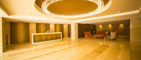A spacious lobby with a reception desk, seating area, and a decorative circular light fixture on the ceiling.