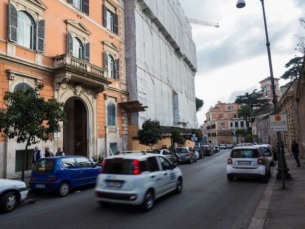 Una calle con coches aparcados y un gran edificio en construcción.