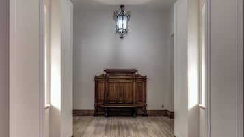 Un pasillo con un banco de madera, una lámpara de pared y un suelo de mármol.