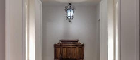Un pasillo con un banco de madera, una lámpara de pared y un suelo de mármol.