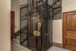 A staircase with a metal railing, a wooden door, and a metal gate. - Operà Suites Roma (Rome)