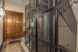 A wooden door with a plaque, a metal gate with a chain, and a stone wall. - Operà Suites Roma (Rome)