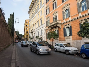 Una calle bordeada de edificios de varios pisos, coches estacionados y una acera.