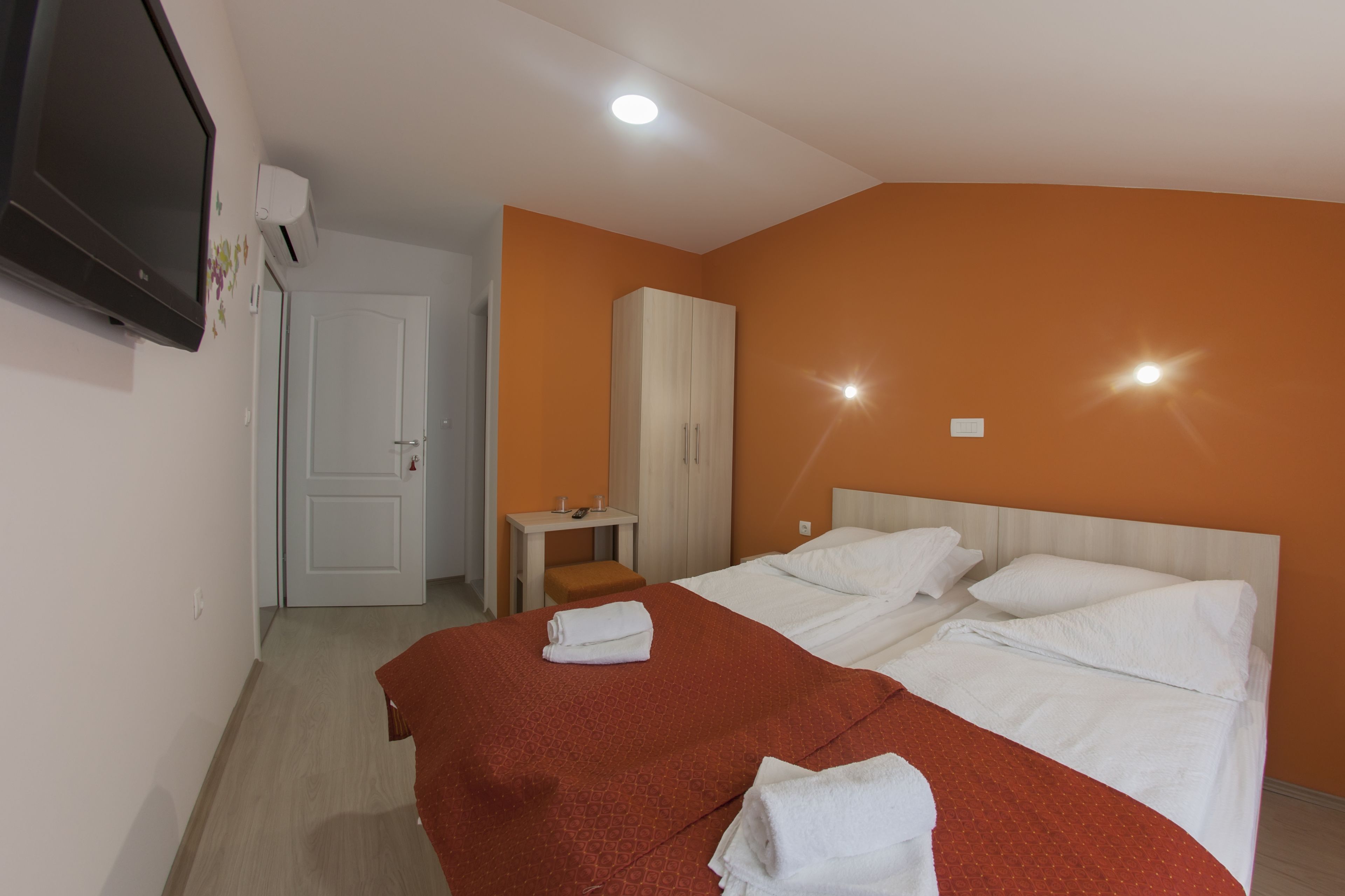 Une chambre d’hôtel avec deux lits, une télévision, une armoire, un bureau et un miroir.