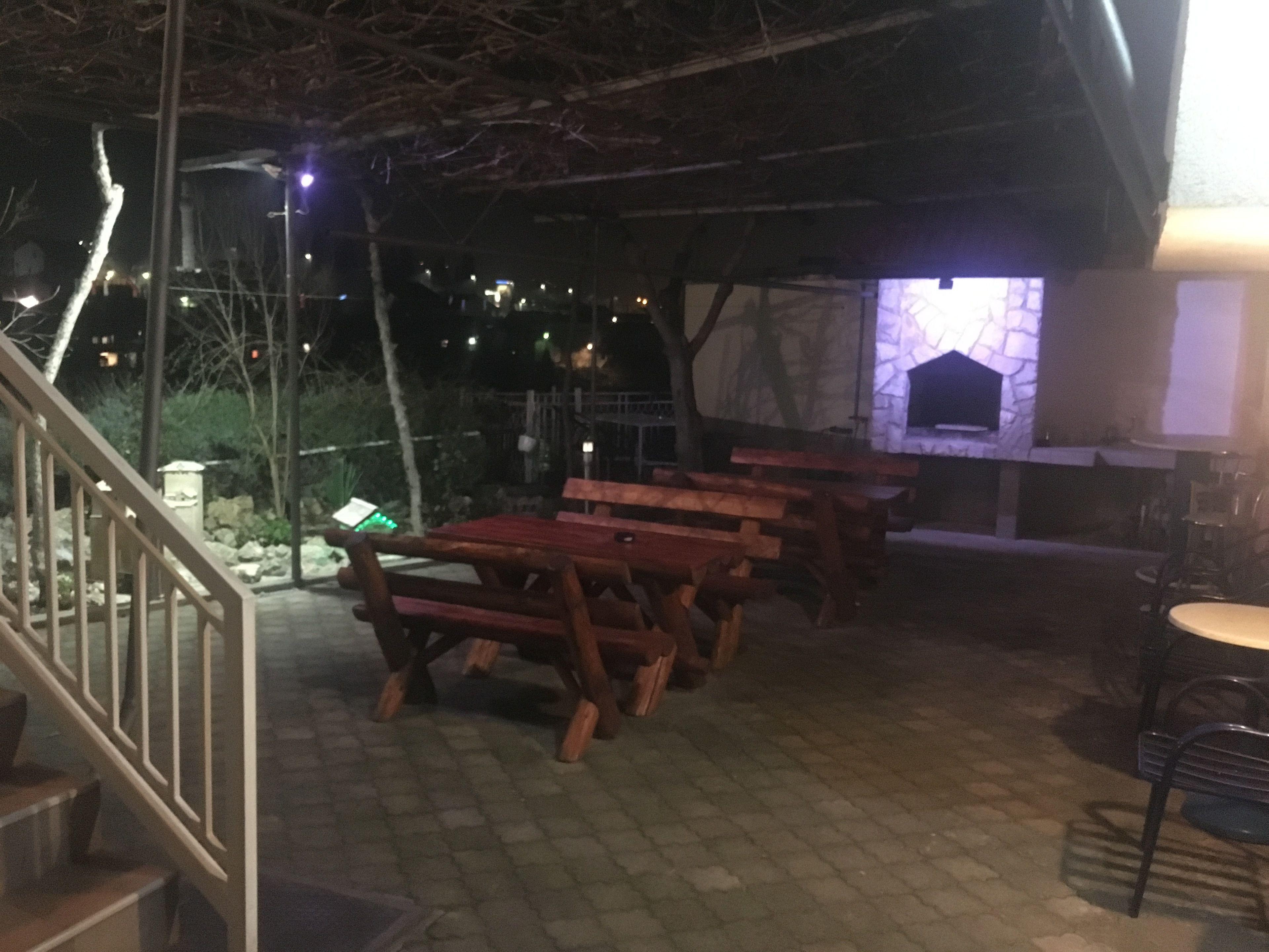 An outdoor patio area with wooden benches and a stone fireplace.
