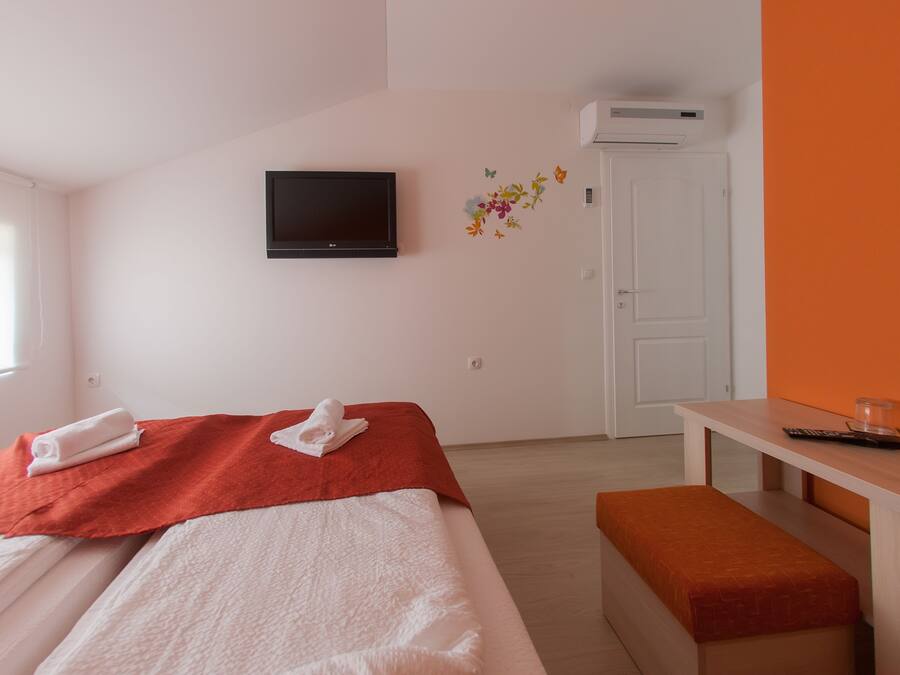 Una camera d'albergo con un letto, una televisione, una panca e una scrivania.