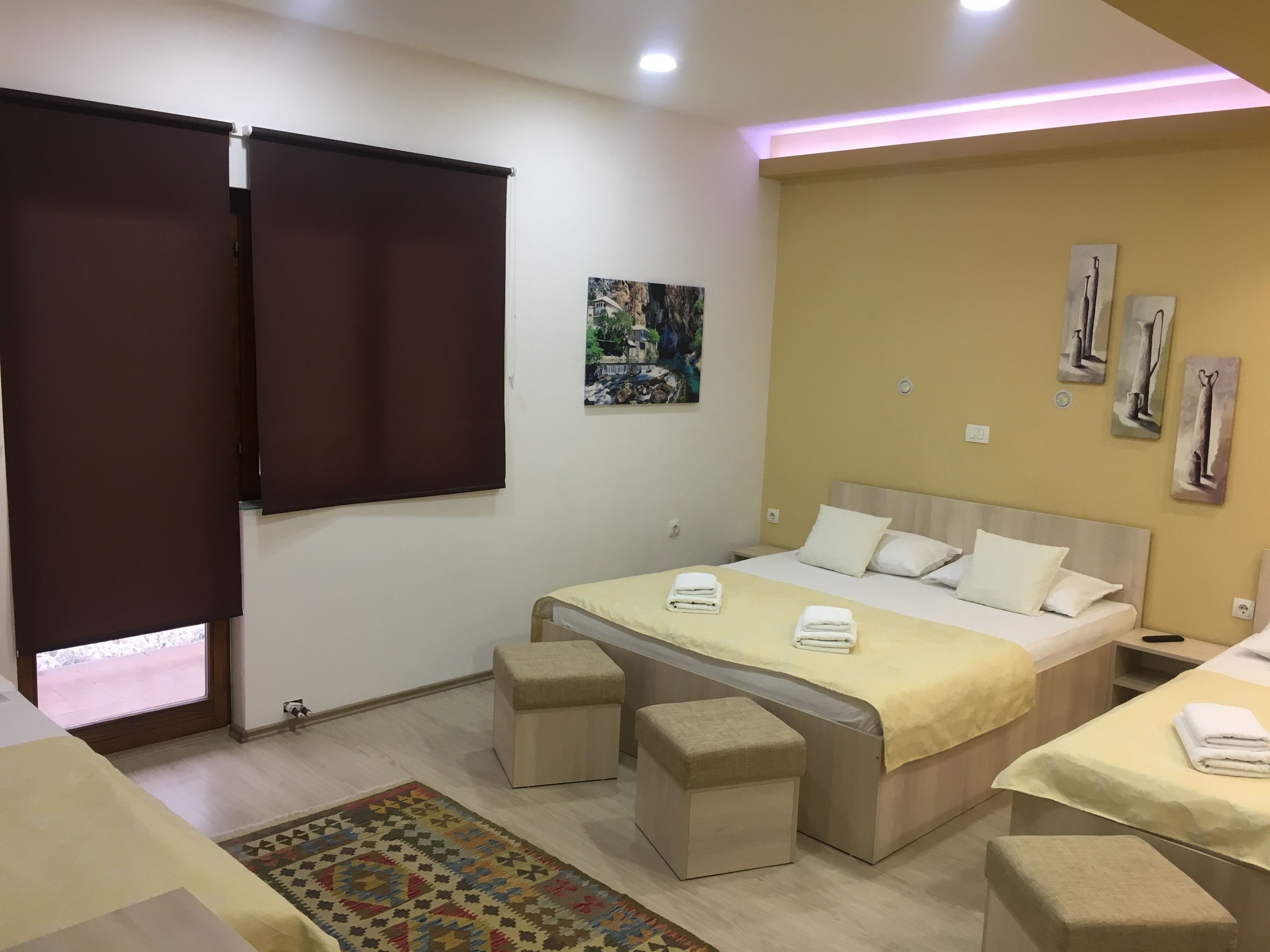 A modern bedroom with a bed, bedside tables, a small rug, and artwork on the wall.