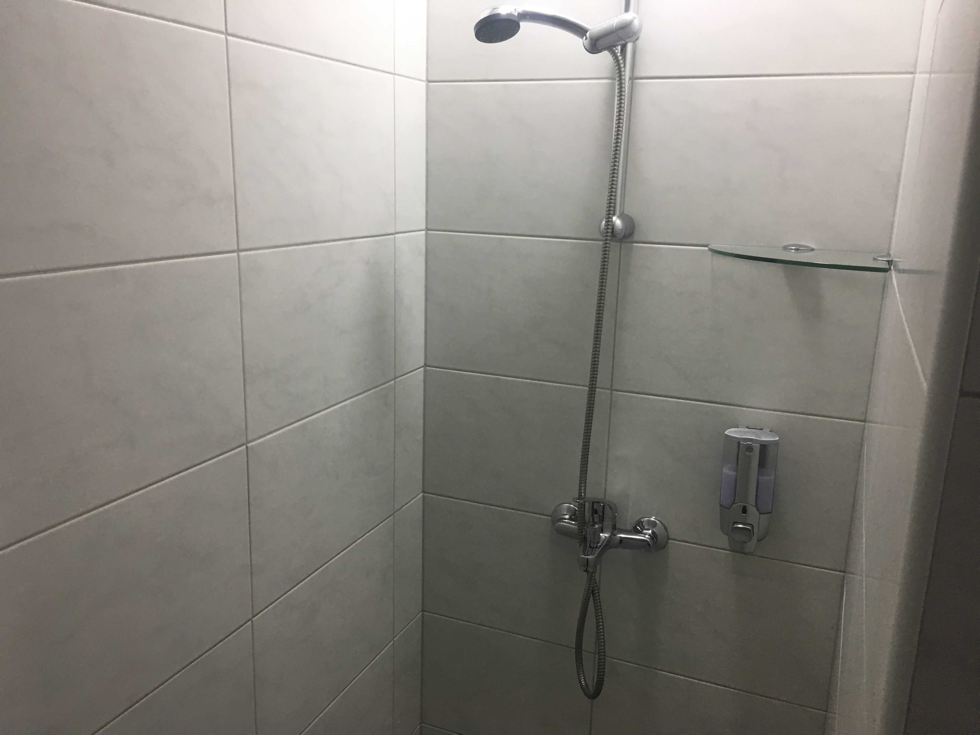 Una doccia con soffione a mano e rubinetto a parete.