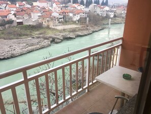 Un balcón con vistas a un río, una mesa y una silla.