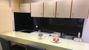 A modern kitchen with a glass island, two black bar stools, and a plate of oranges. - Guest House City Star (Mostar)