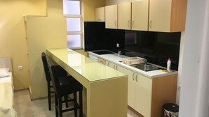 A compact kitchen with a central island, black bar stools, and a window. - Guest House City Star (Mostar)