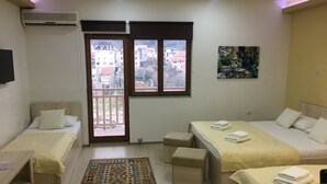 A hotel room with two single beds, a small desk, a chair, a patterned rug, and a balcony with a view of buildings. - Guest House City Star (Mostar)