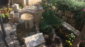 A model of a castle with a bridge, surrounded by a garden with various plants and flowers. - Guest House City Star (Mostar)