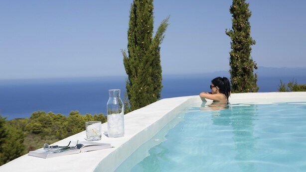 A person relaxing in a infinity pool with a clear view of the sea and mountains. - Boo Premium Living Villas (Lefkada)