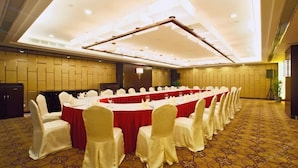 A conference room with a long table, white chairs, and a patterned carpet. - Cenbest Jinling Grand Hotel (Wuhu)