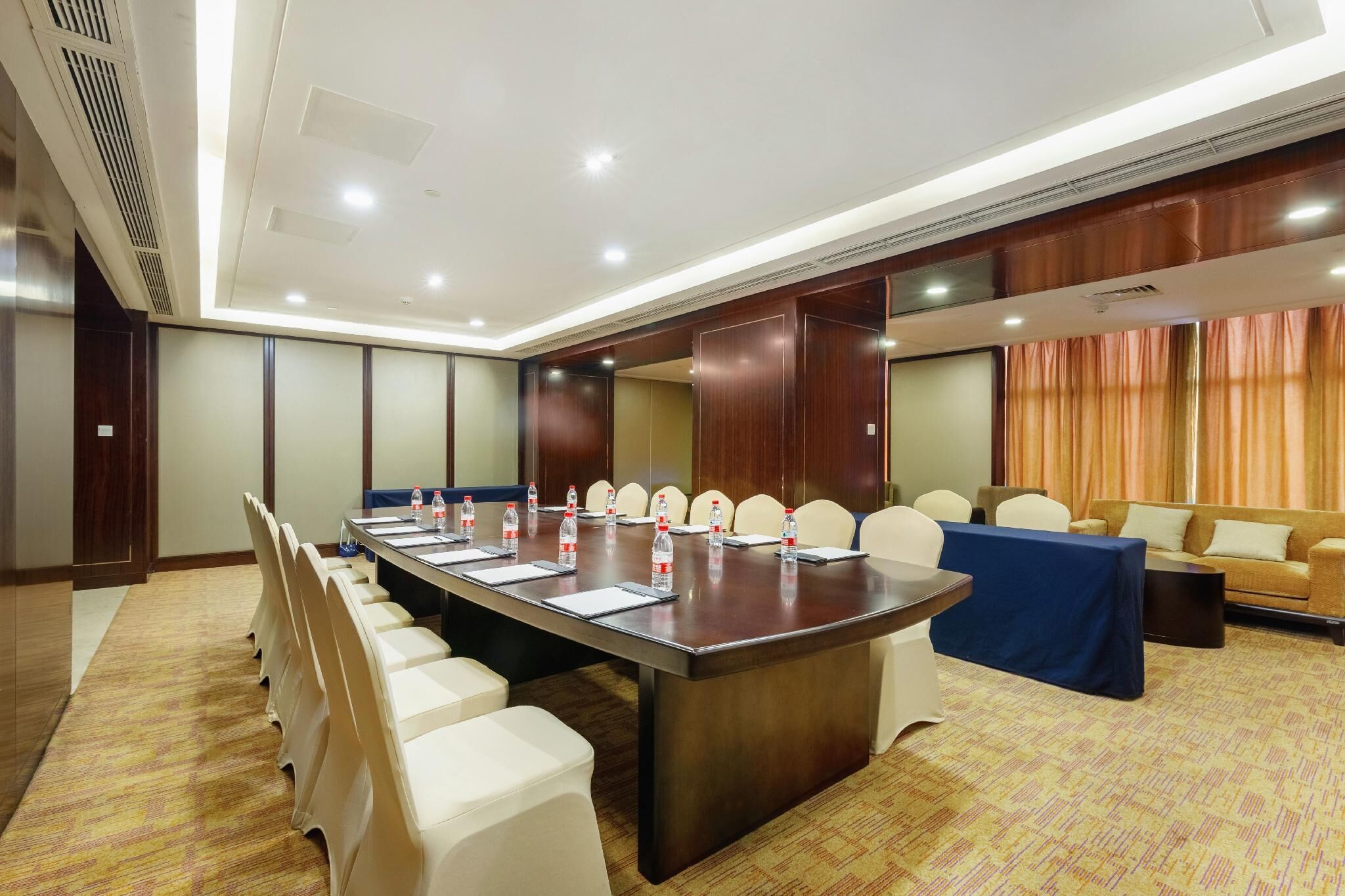 A conference room with a long table, chairs, and a sofa.