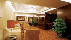 A hotel lobby with a reception desk, seating area, and a television. - Cenbest Jinling Grand Hotel (Wuhu)