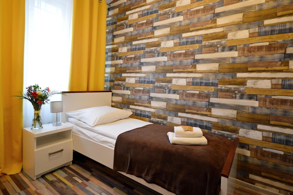 Una habitación de hotel con una cama, una mesita de noche, una lámpara y una pared con diseño de tablones de madera.