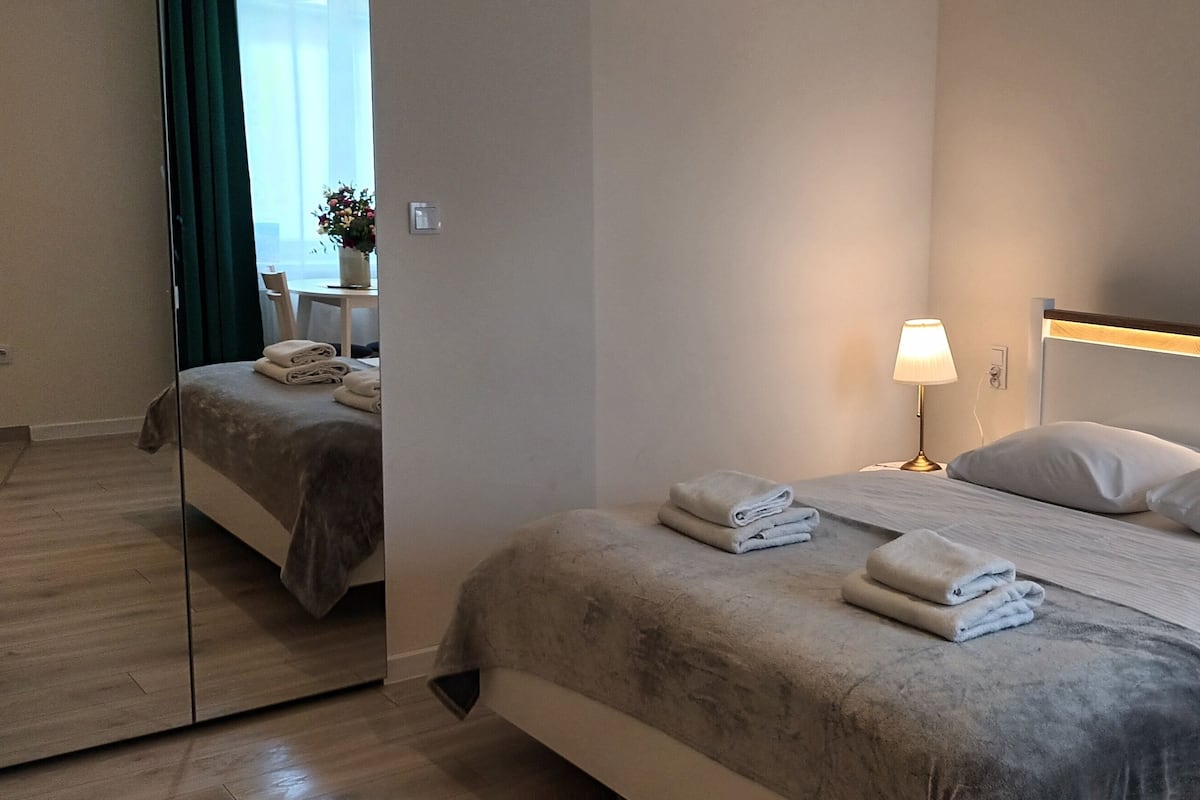 Una habitación de hotel moderna con una cama grande, dos lámparas de noche y un espejo.