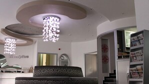 En moderne reception med en stribet sofa, et receptionistskranke og en trappe til en etage ovenover.