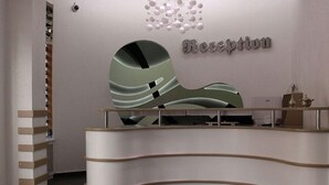 Et moderne receptionsområde med en buet skranke og et vægmonteret skilt med teksten "Reception".