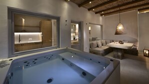 A modern bathroom with a large bathtub, a sofa, and a dining table. - VLIA Myconian Residences (Mykonos)
