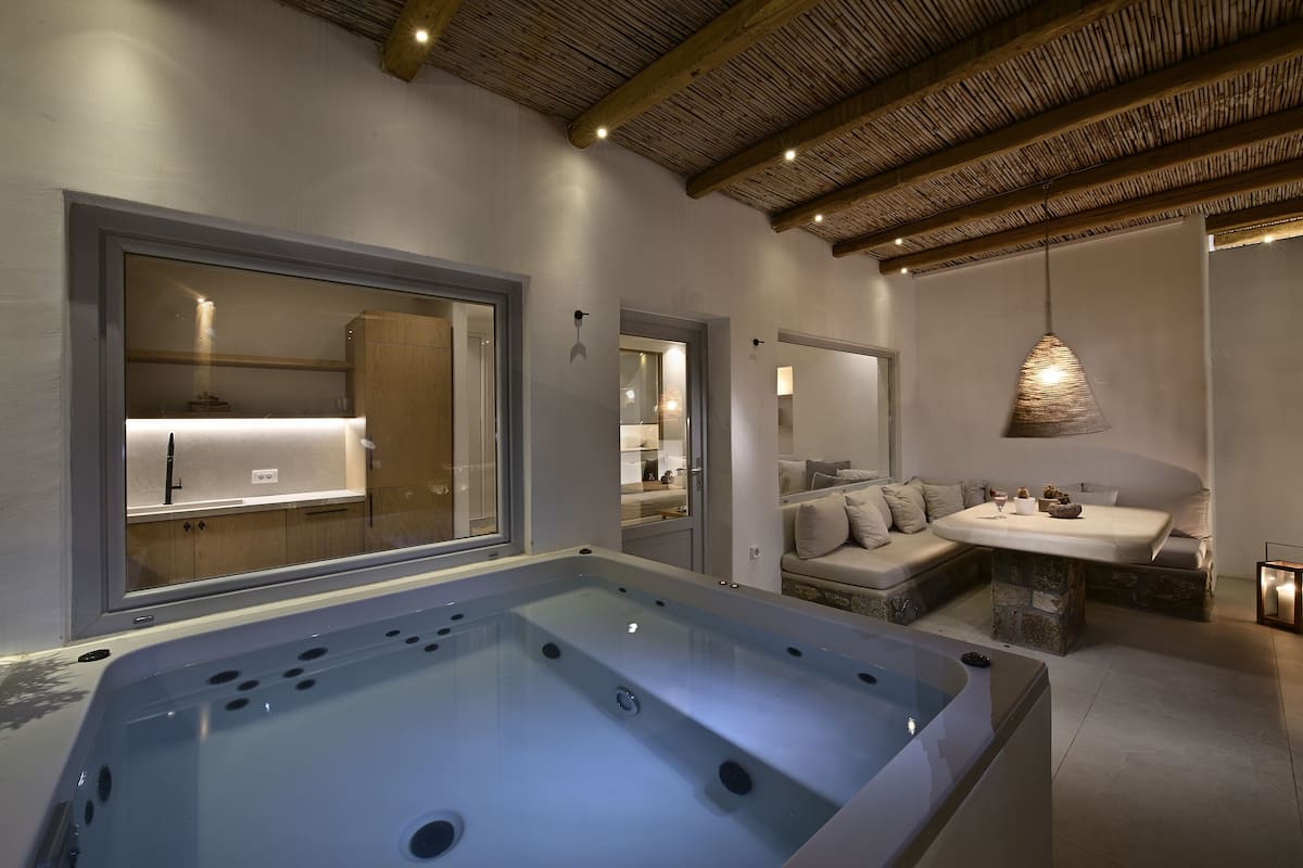 A modern bathroom with a large bathtub, a sofa, and a dining table.