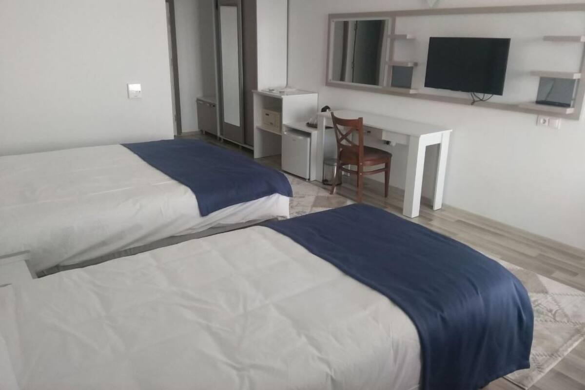 A hotel room with two beds, a desk, a chair, a TV, and a wardrobe.