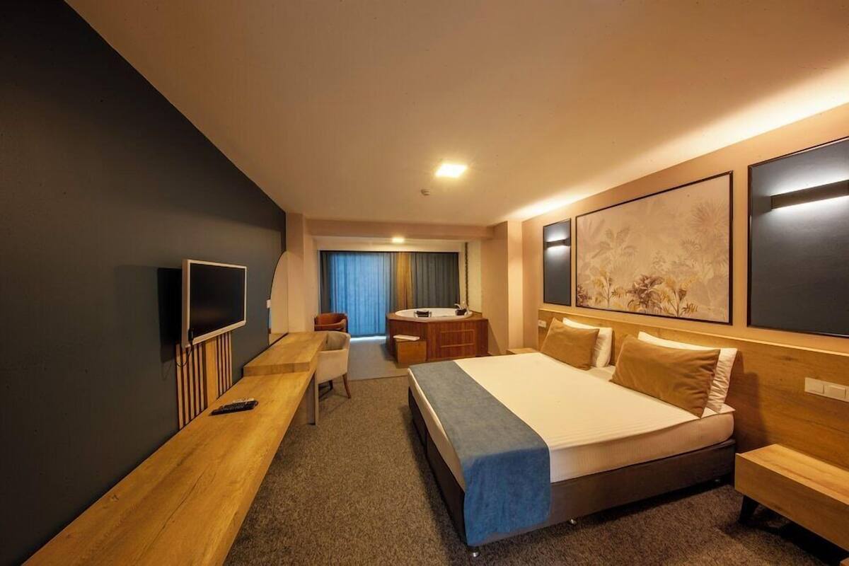 Ein Hotelzimmer mit Bett, Schreibtisch, Fernseher und einem durch eine Tür sichtbaren Badezimmer.