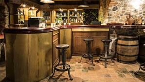 A bar area with a wooden bar counter, stools, and a stone wall. - Hotel pod Cizemka (Sandomierz)
