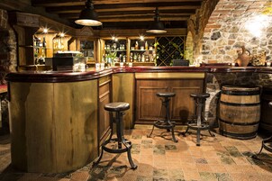 Uma área de bar com balcão de madeira, banquetes e parede de pedra.