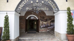The entrance to Hotel Restaurant 1563 Pod Ciemka with a brick facade and a decorative metal archway. - Hotel pod Cizemka (Sandomierz)