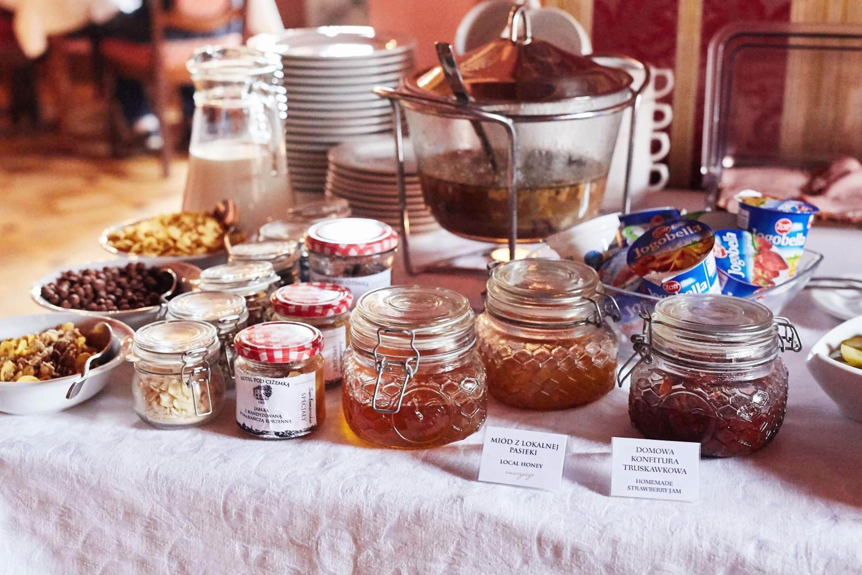 A table with various jars of homemade jams and honey, along with some packaged snacks.