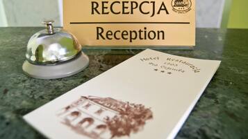 A hotel reception area with a reception desk, a bell, and a sign labeled "RECEPTION".