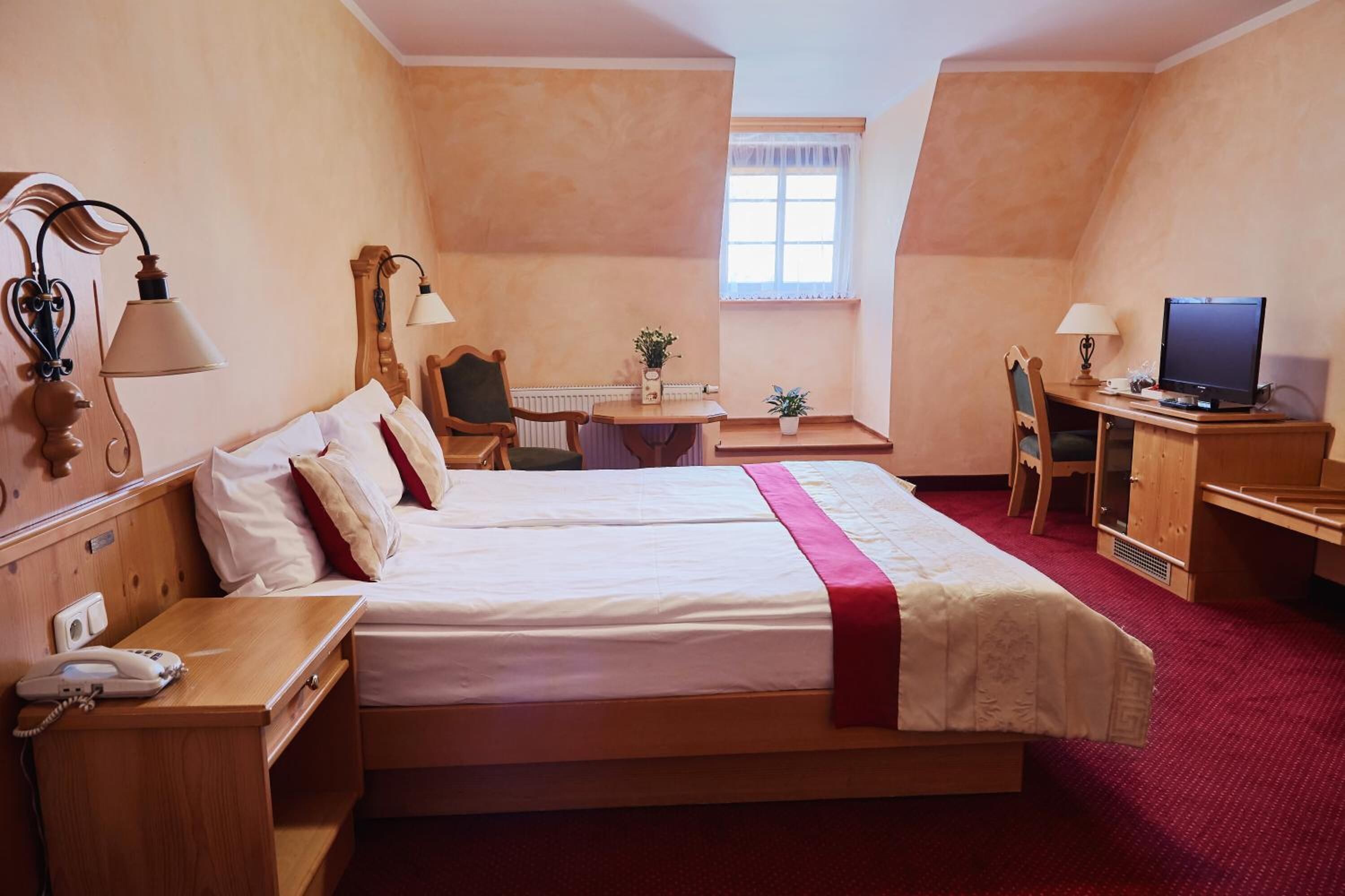 Habitación de hotel con dos camas, un escritorio, una silla, un televisor y un teléfono.