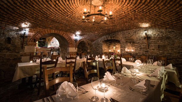 A restaurant with stone walls, wooden tables, and a brick ceiling. - Hotel pod Cizemka (Sandomierz)