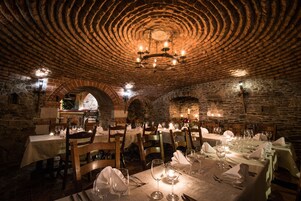 Um restaurante com paredes de pedra, mesas de madeira e teto de tijolos.