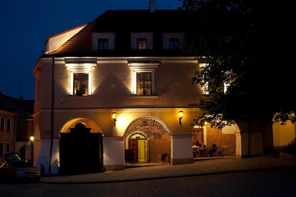 A two-story building with a brick facade, arched entrance, and illuminated windows.