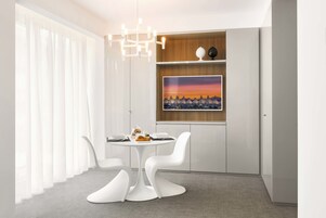 A modern dining area with a round table, white chairs, and a chandelier.