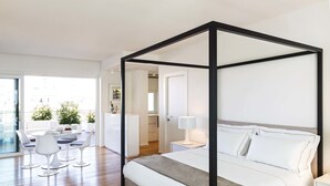 A modern bedroom with a four-poster bed, a dining area with white chairs, and a view of the city through large windows. - Dilman Luxury Stay (Bari)