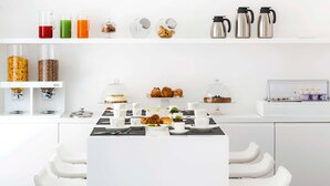 A modern breakfast setup with a variety of food items and beverages on a white table, accompanied by white chairs. - Dilman Luxury Stay (Bari)