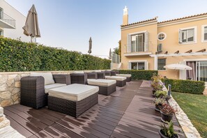 Une terrasse avec des sièges d’extérieur, un mur en pierre et une haie.