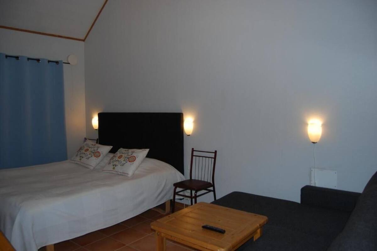 Une chambre à coucher avec un lit, une chaise, un canapé et une petite table.