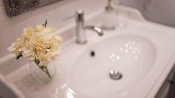 A bathroom sink with a vase of flowers and a mirror above it.