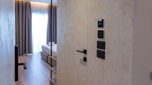 A modern hotel room with a large wardrobe, a bed, and a view of the outdoors. - Arel Hotel (Sarandë)