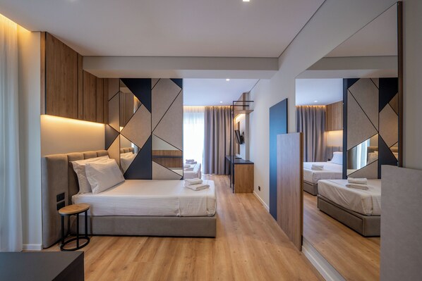 A modern hotel room with a large bed, a small side table, and a mirror reflecting the room. - Arel Hotel (Sarandë)