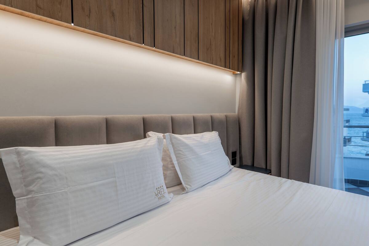 A hotel room with a large bed, a wooden headboard, and a view of the city.